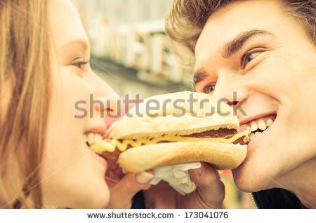 cute couple sharing a hot dog at the same time