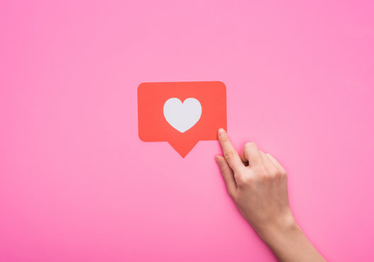 hand pointing to like icon on pink background