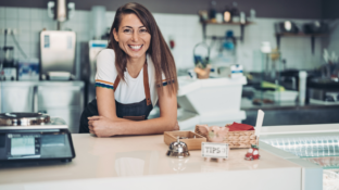 A small business owner sitting at a counter with a wide smile. Hot Dog Marketing