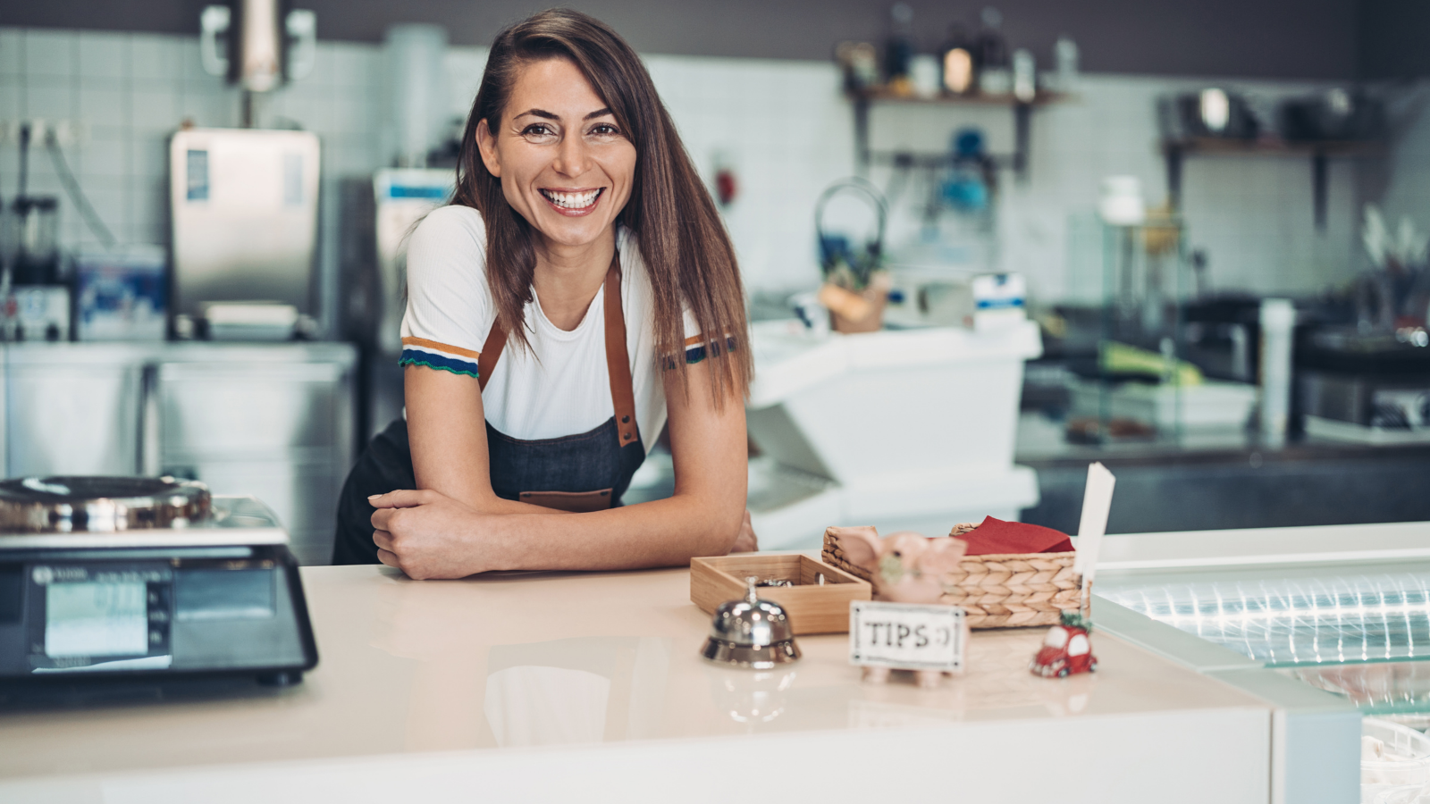 A small business owner sitting at a counter with a wide smile.