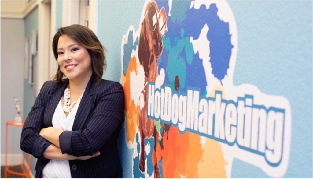 Jessica Scanlon, CEO of Hot Dog Marketing, an Austin Texas Marketing Company poses for photo in front of company mural